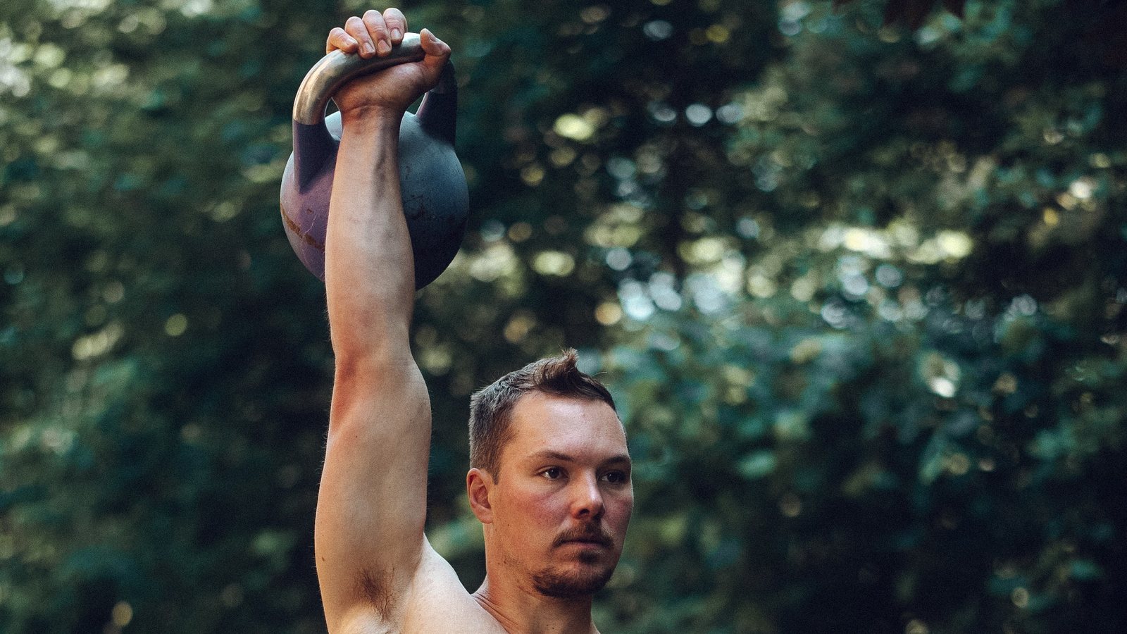 Tim hält eine Kettlebell über dem Kopf