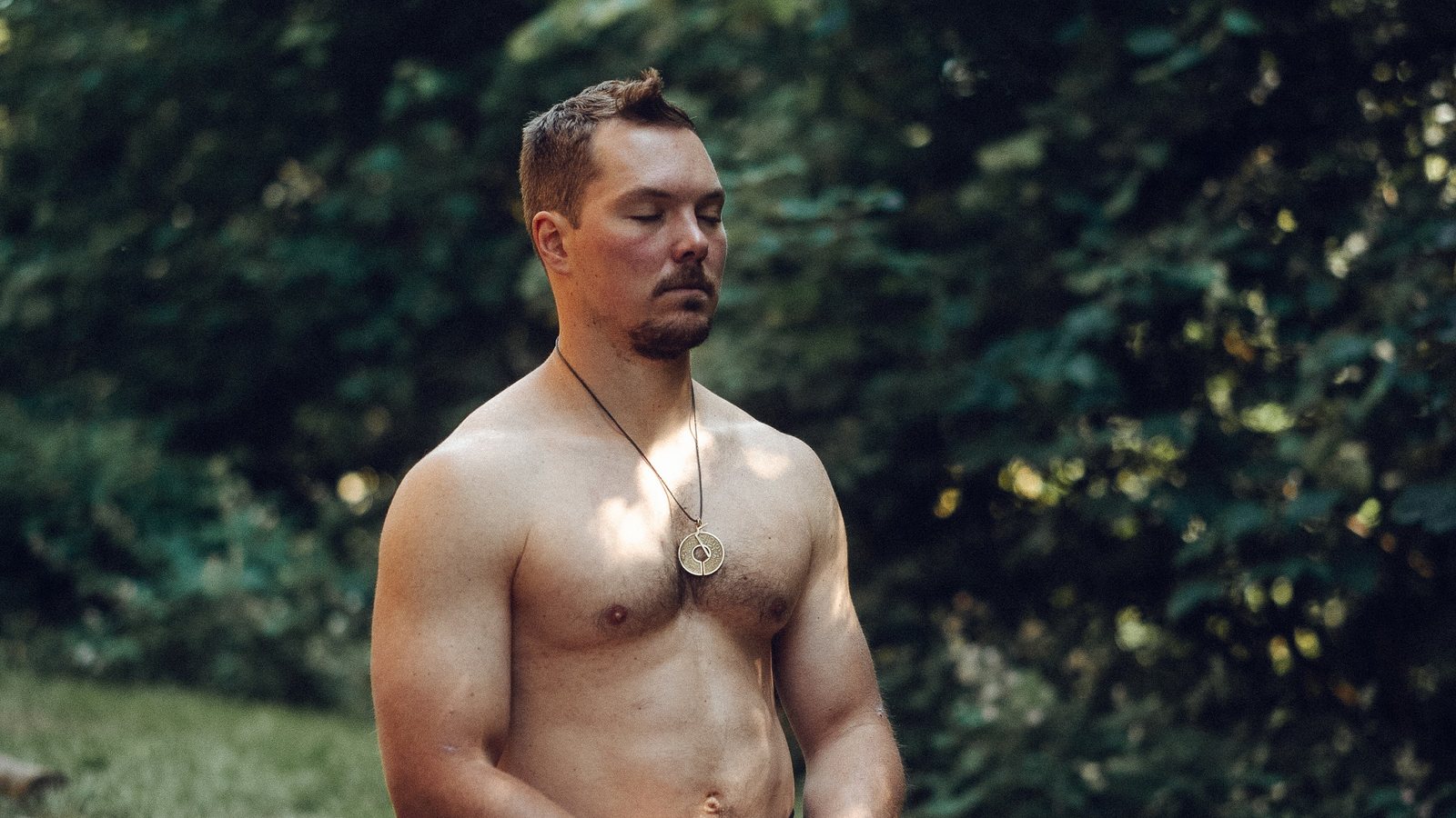 Tim kniet im Garten und meditiert mit geschlossenen Augen