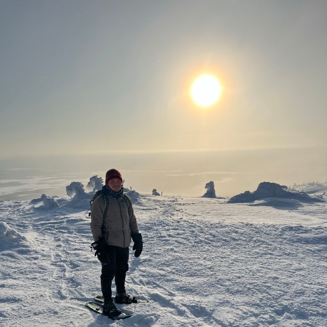 Tim Böttner im Schnee auf einem Berg, hinter ihm die Wintersonne